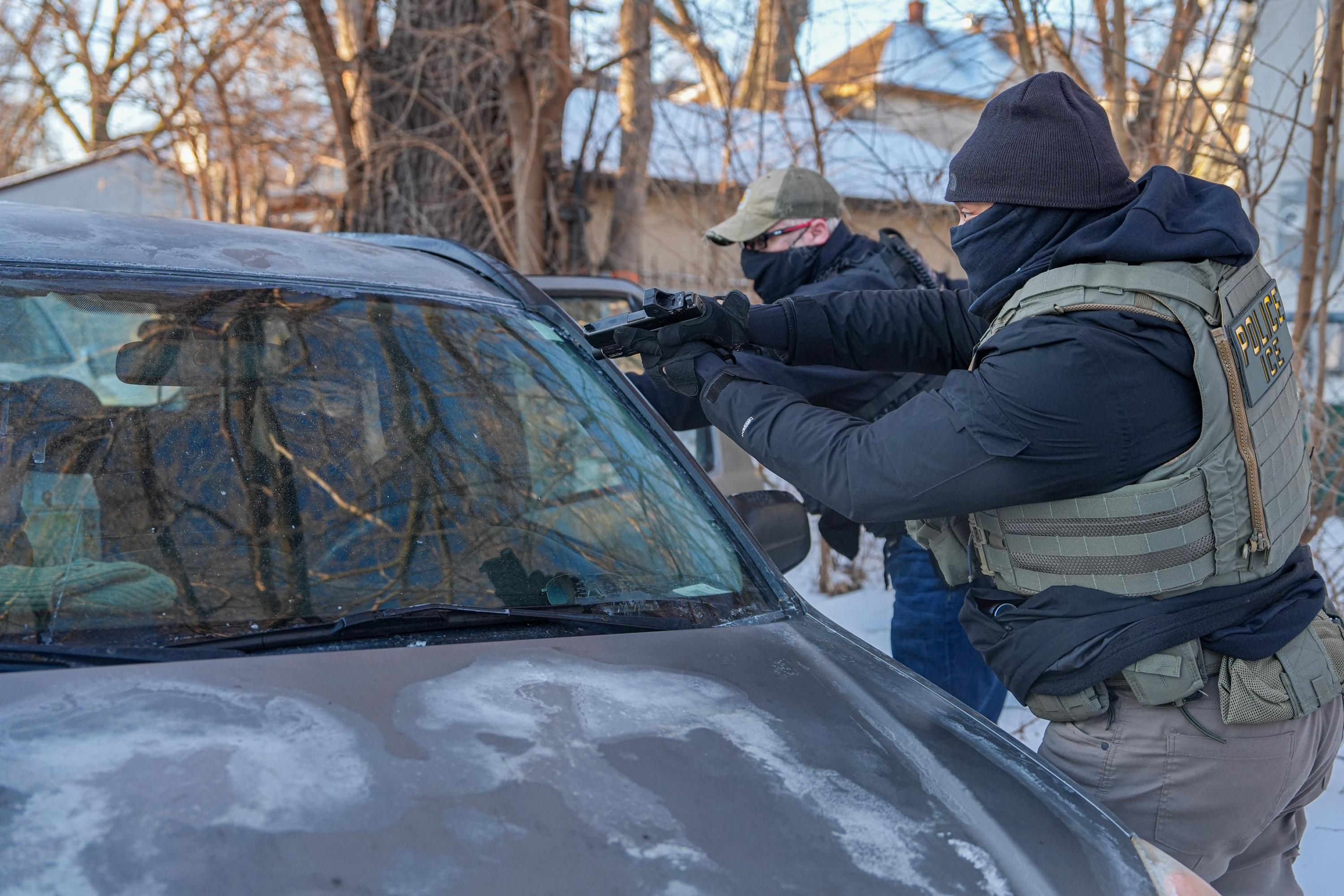 Activists are approached by a federal agent brandishing a firearm,...